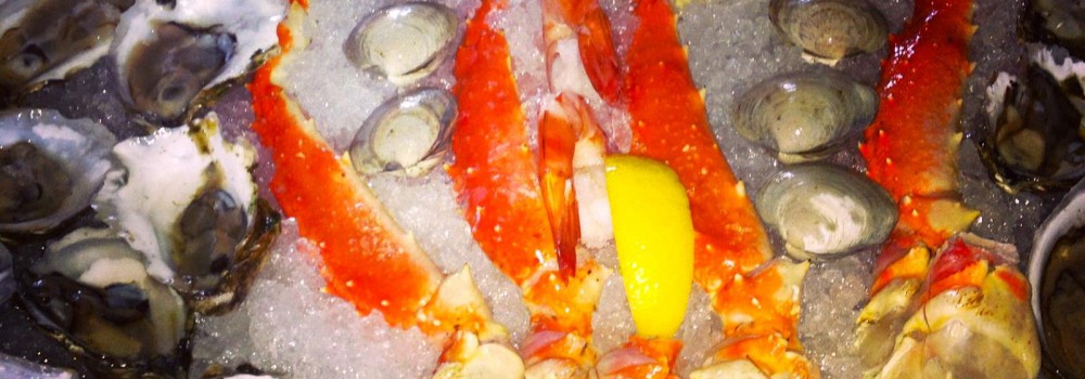 Oysters on a bed of ice surrounding shrimp, all on a plate