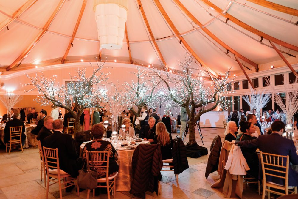 Wedding guests on dance floor under salmon-colored tent at night