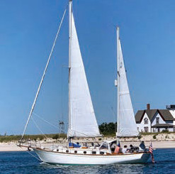 Two masted sailboat on the water with beach in background