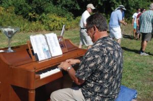 Man playing piano outside in the woods